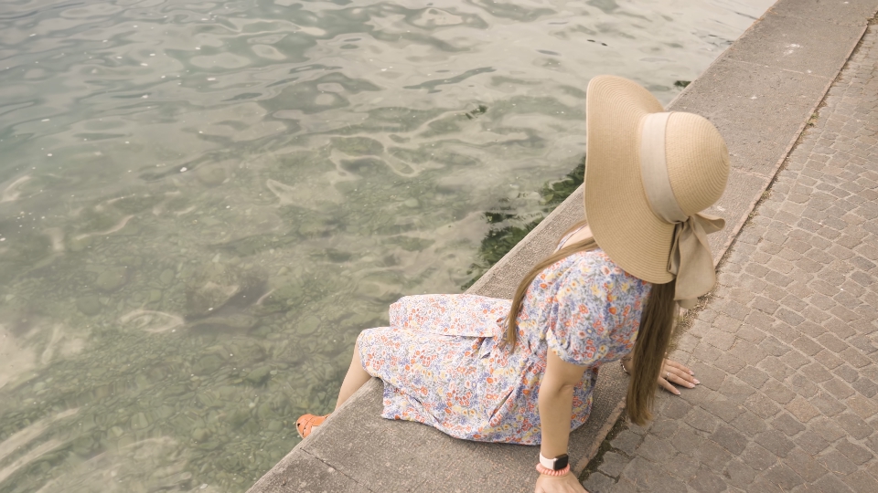 Woman sits on embankment looking at sunlight on water