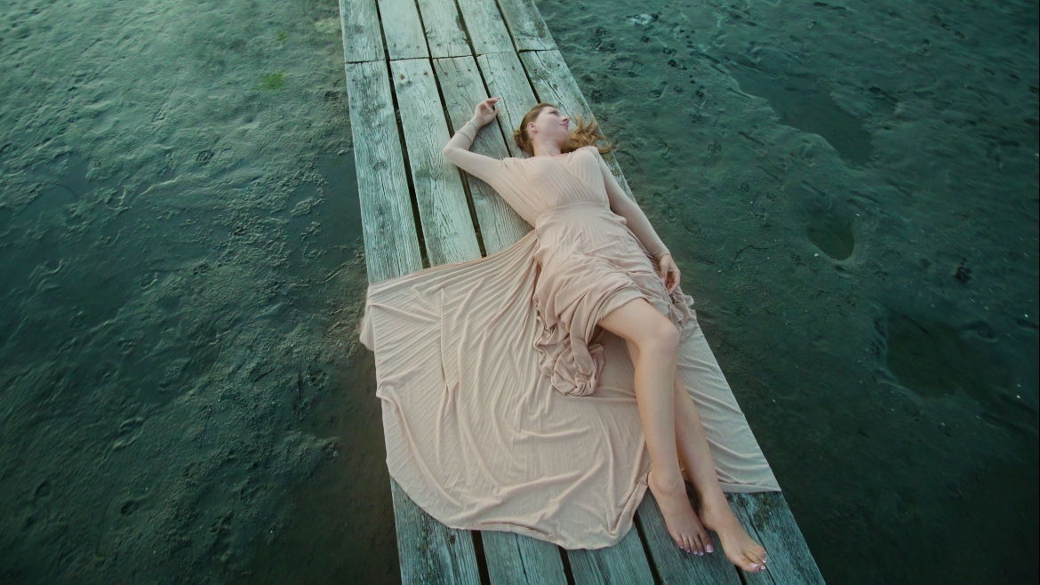 Donna elegante sdraiata sul molo in legno