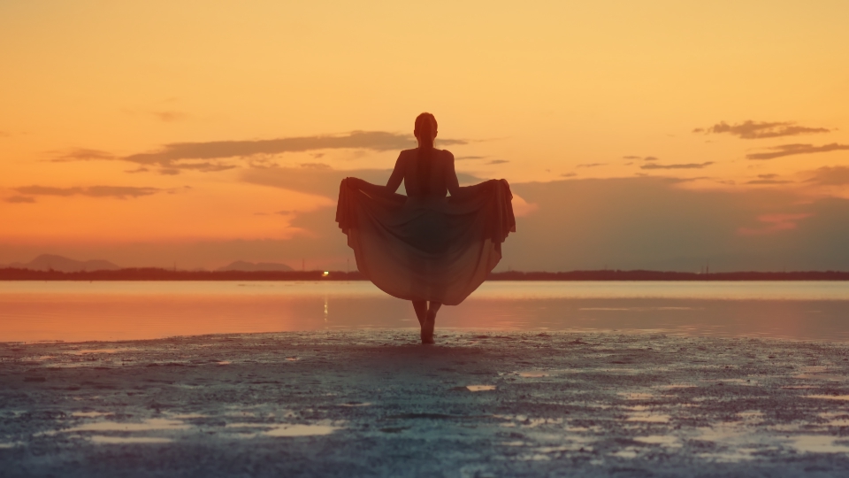 Donna cammina sulla laguna al tramonto rosso