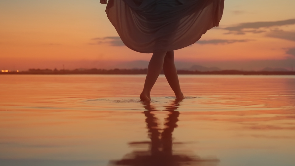 Piedi della donna che cammina scalza sull’acqua