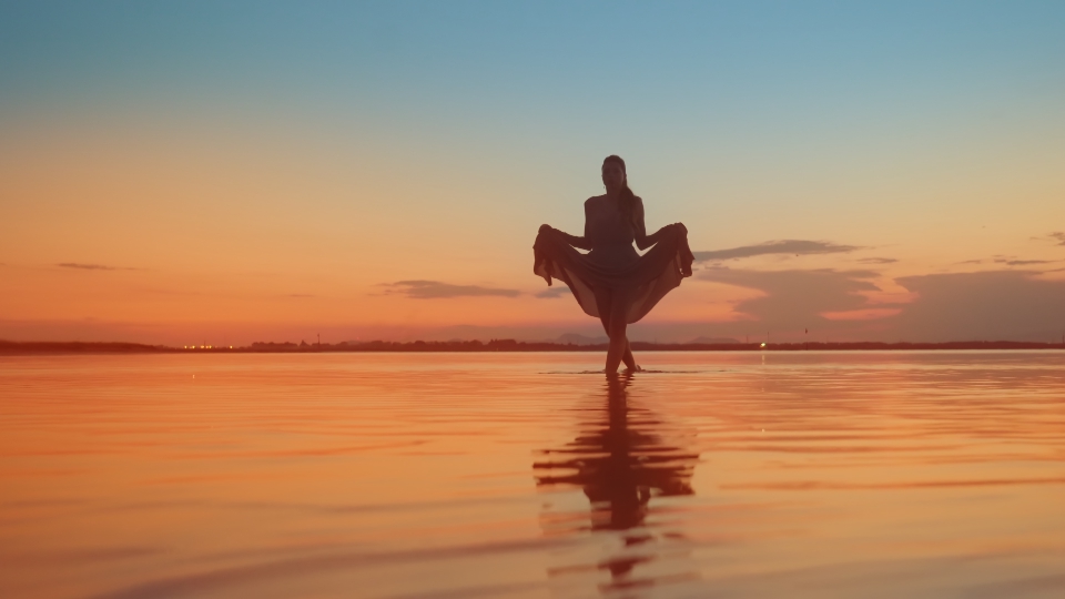 Beautiful sunset and woman walking on the water