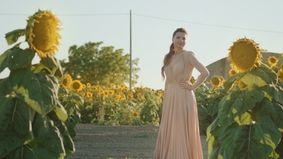 Donna in abito elegante sorride tra girasoli