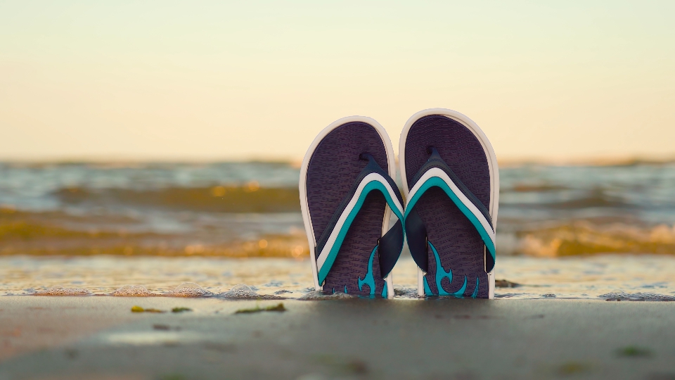 flip flops in the sand of the beach by the sea