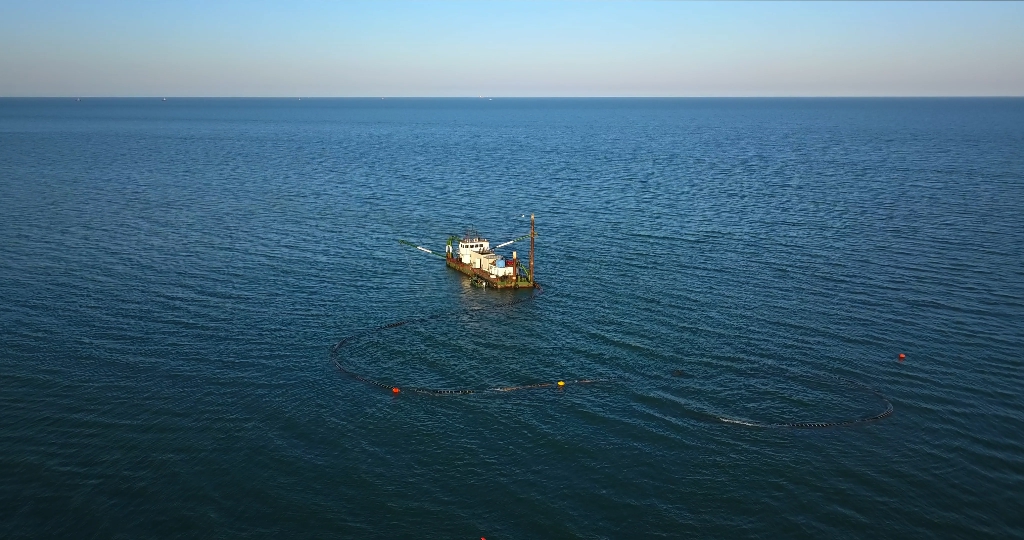 A boat is doing some work in the middle of the sea