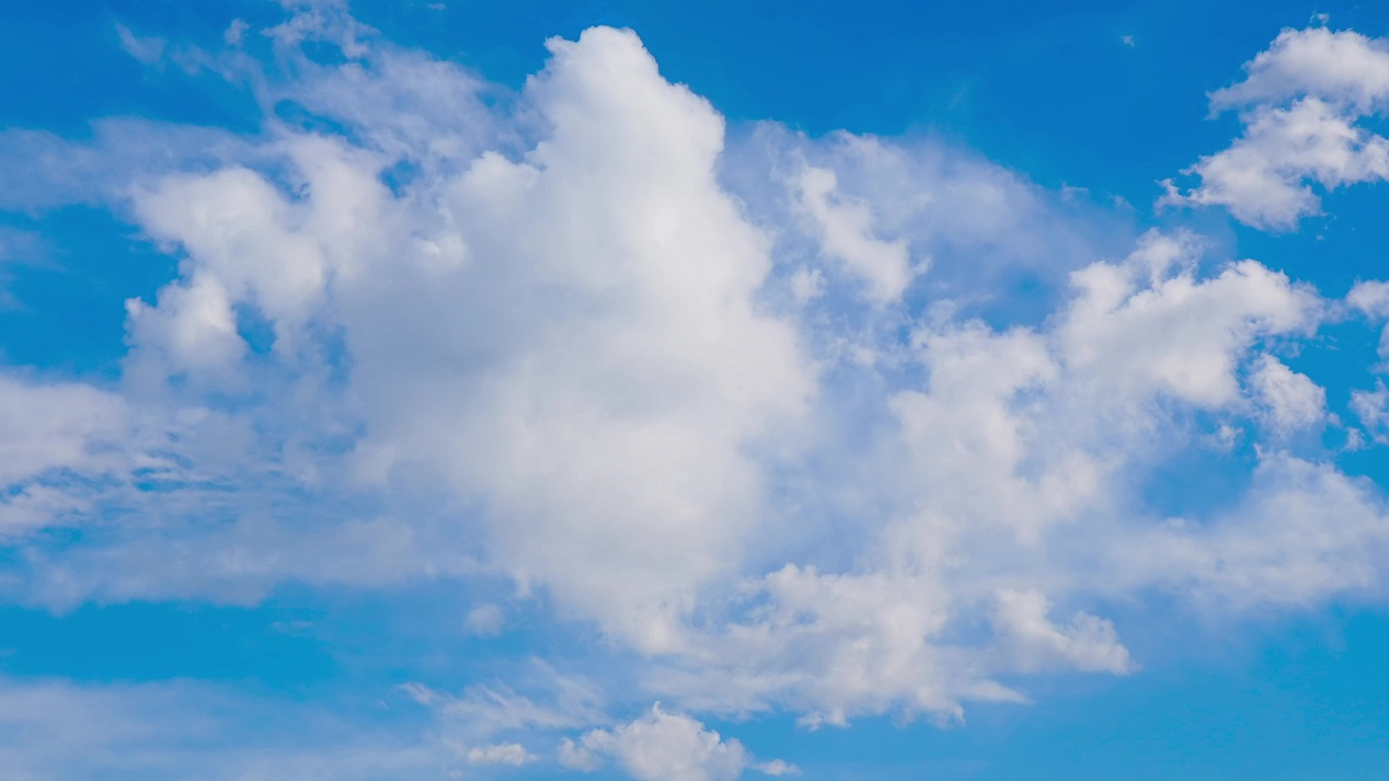 Soft white clouds roll quickly across the blue sky
