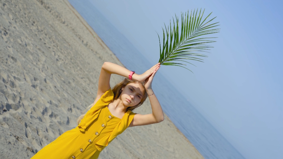 Girl holds in hand a green sheet of flowers on the sea