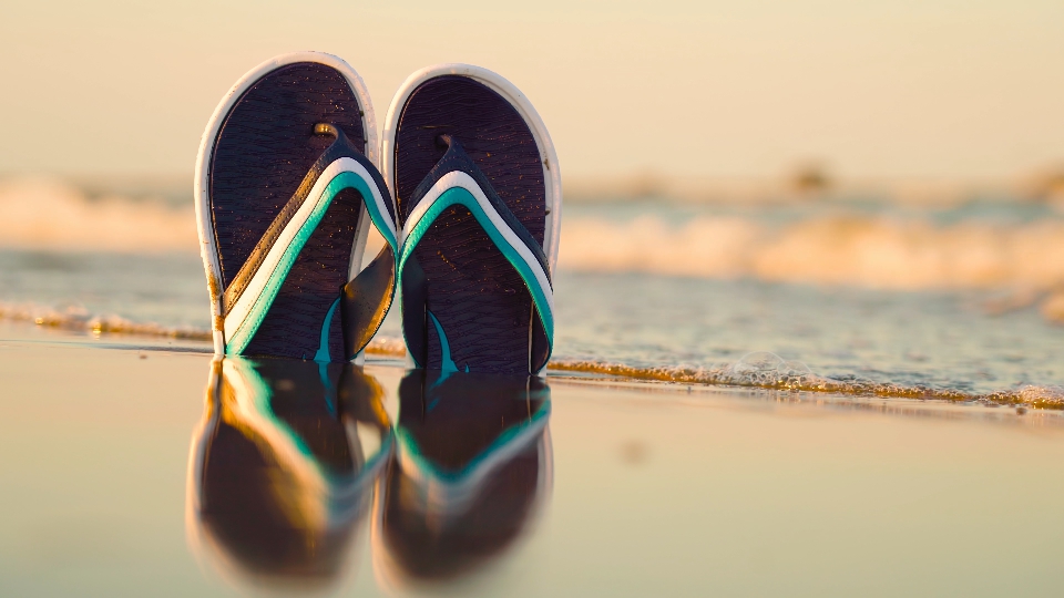 flip flops in the sand of the beach by the sea