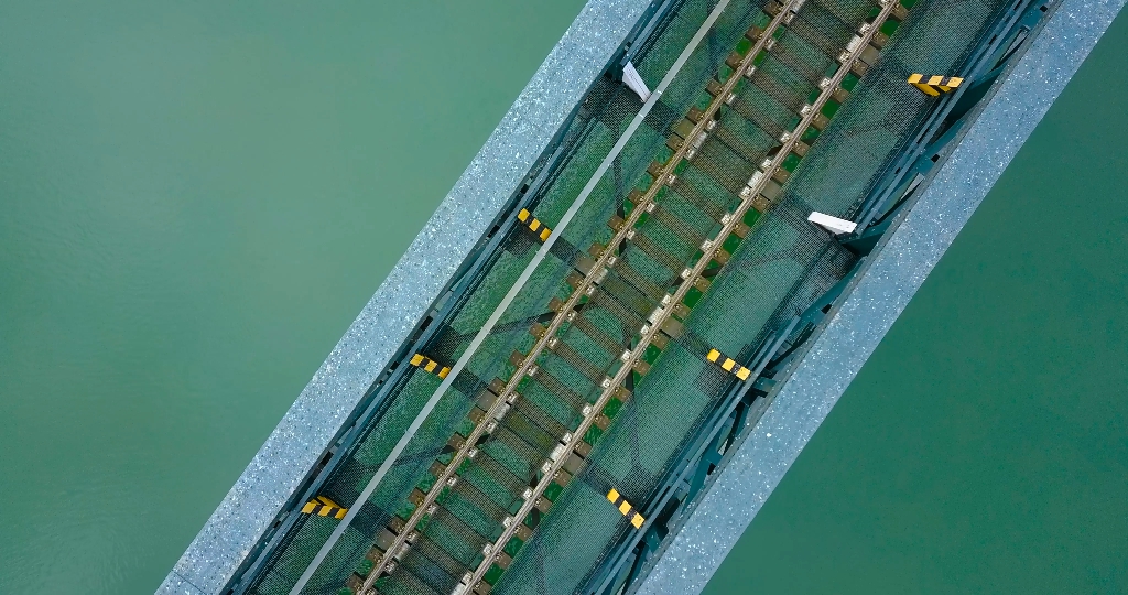 Steel bridge with train tracks from above over a river