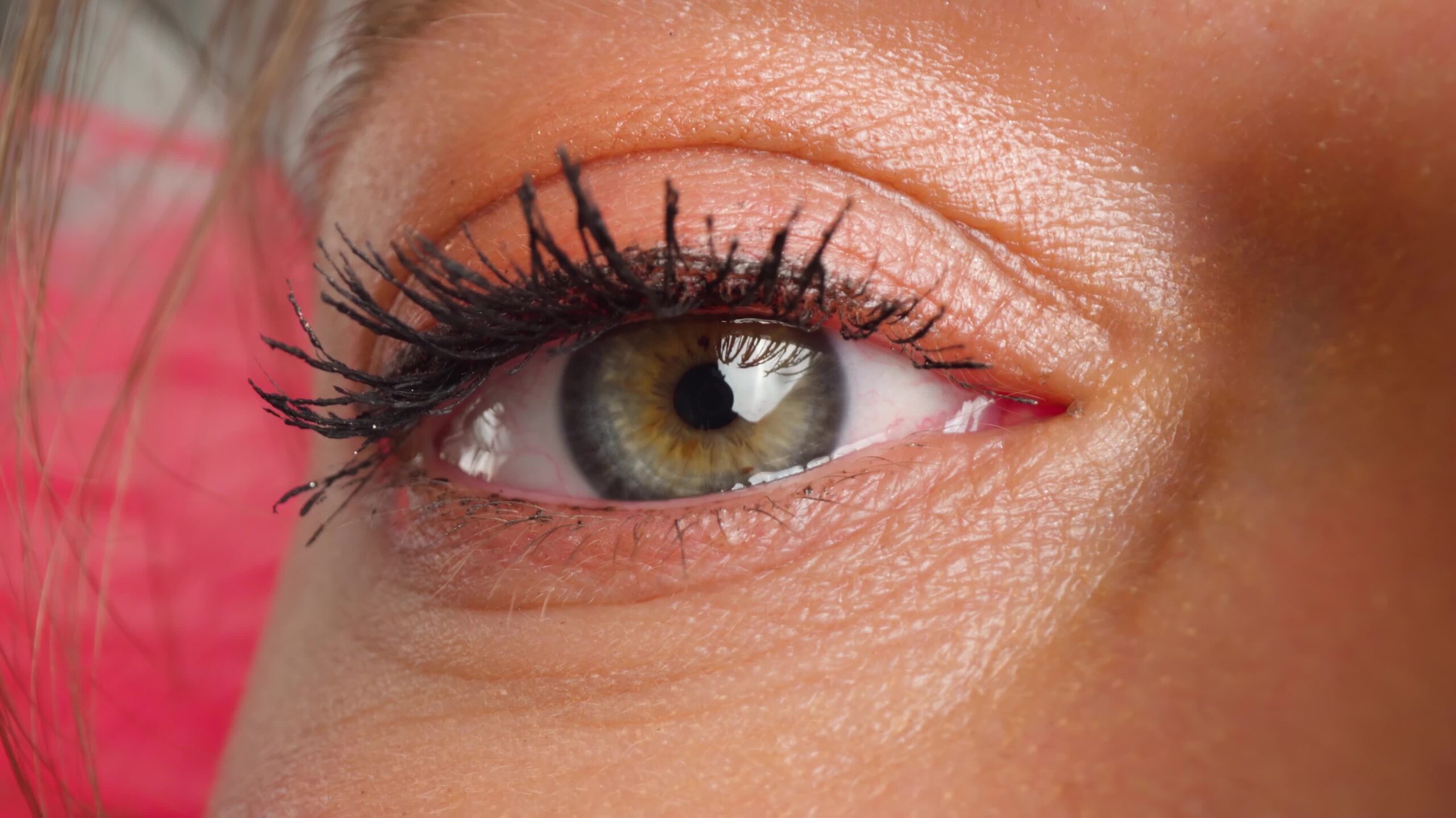 Brown-eyed woman with bright eye makeup looks past camera