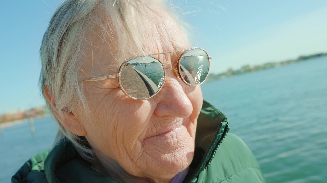 La donna dai capelli grigi con gli occhiali da sole si erge contro la laguna di Venezia