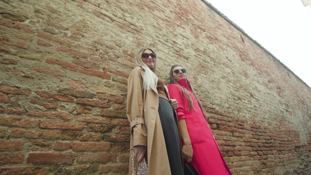 Young girl friends pose at shabby wall of Venetian building