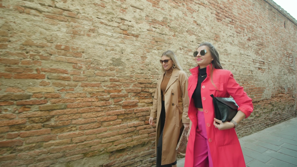 Fashionable Friends Chatting Alongside a Brick Wall in Venice