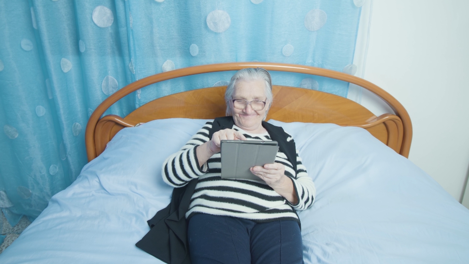 Elderly Woman Engaging with Social Media: Bedtime Connection