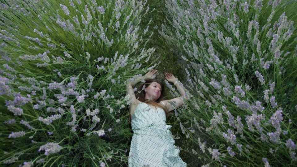 Donna con abito bianco sdraiato nel verde lavanda
