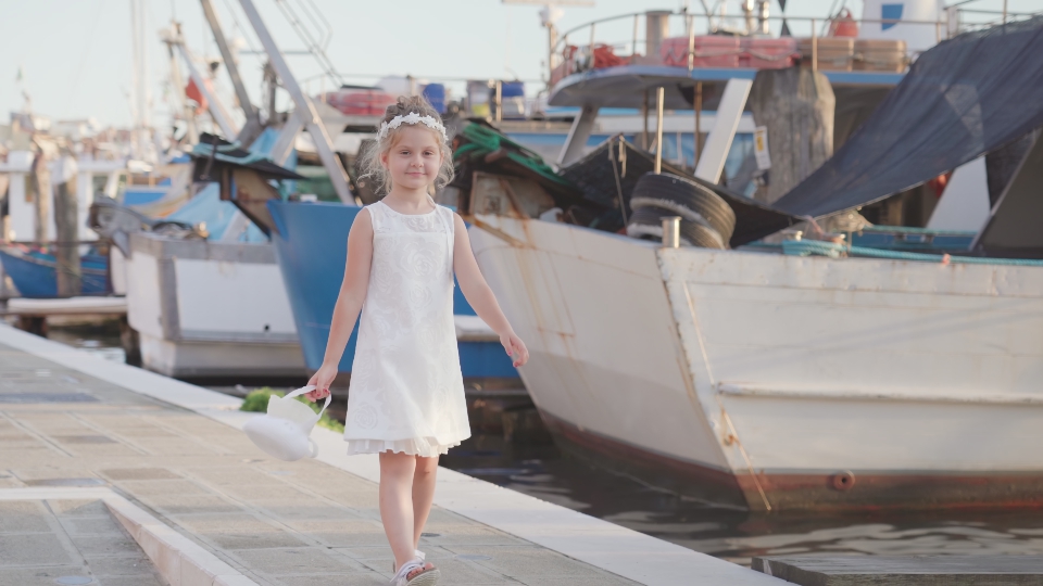 La bambina cammina davanti ai pescherecci