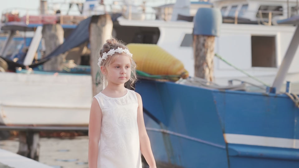 La bambina cammina davanti ai pescherecci