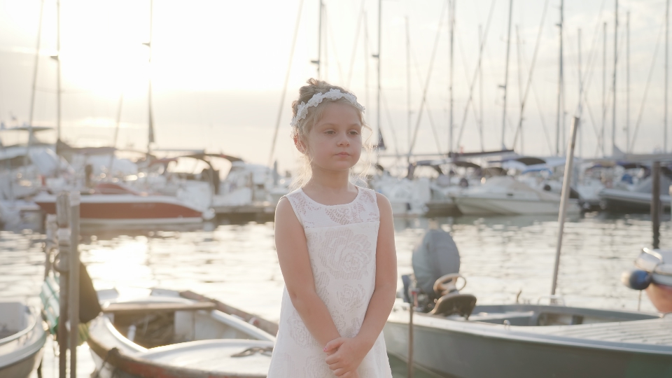 Little girl stops at sunset in front of the boats