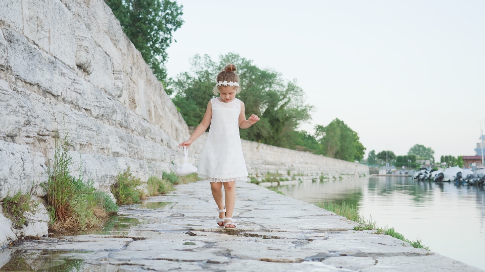 Little girl dressed in white runs near the river