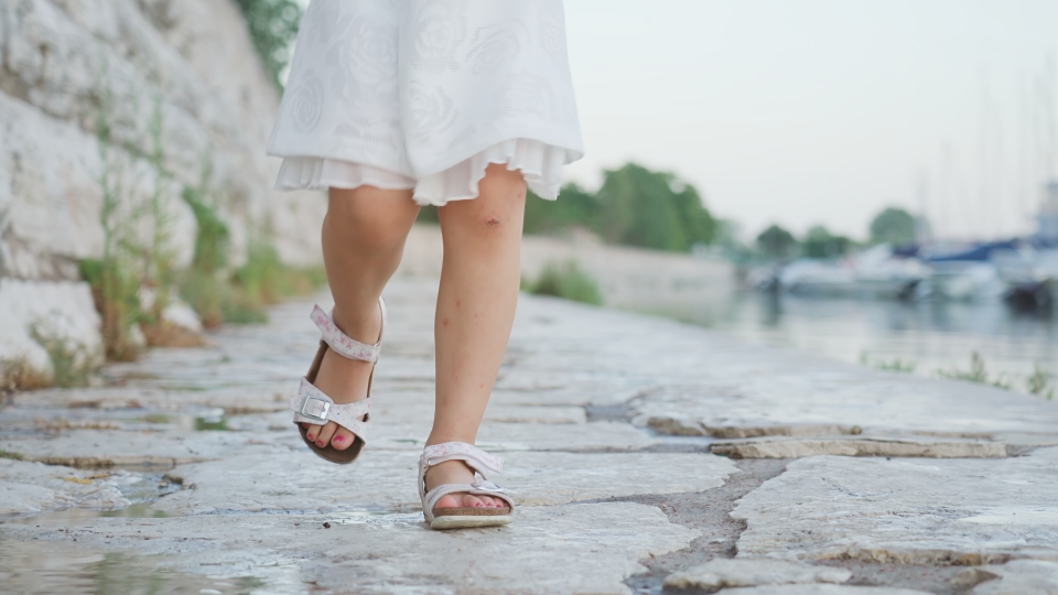 La bambina vestita di bianco corre sulle pietre