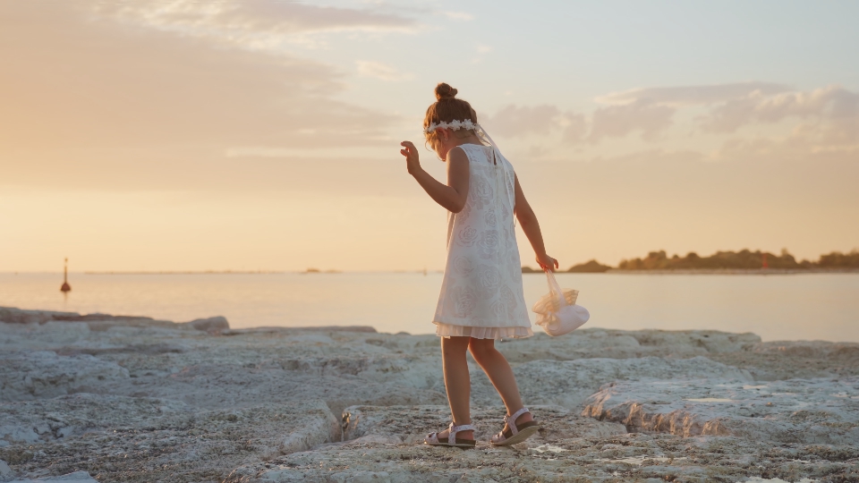 Little girl walks on the stones at the river