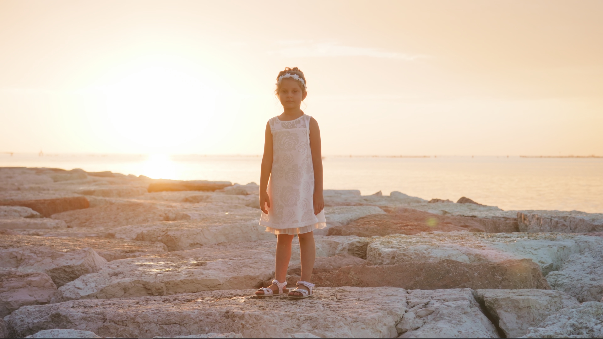 Bambina in piedi al tramonto sulla laguna