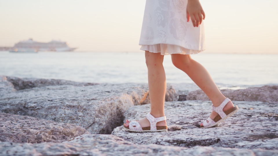 Gambe della bambina che cammina sulle pietre