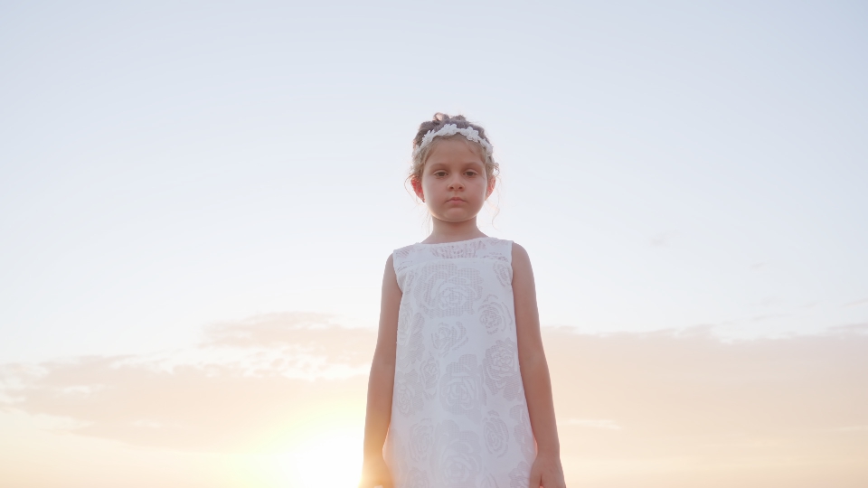 Bambina in bianco sullo sfondo del cielo