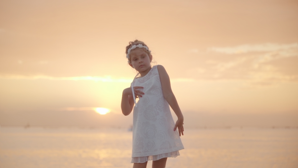 Little girl dances funny at sunset
