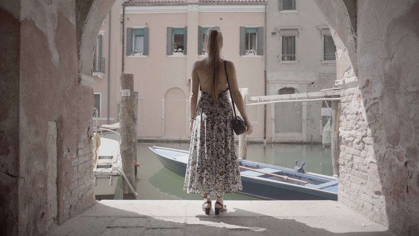 Woman looks at the boat on the water of the Venetian canal