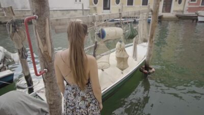 Sea Traditions: Woman Performs Gestures in Front of a Boat with Fishing Nets
