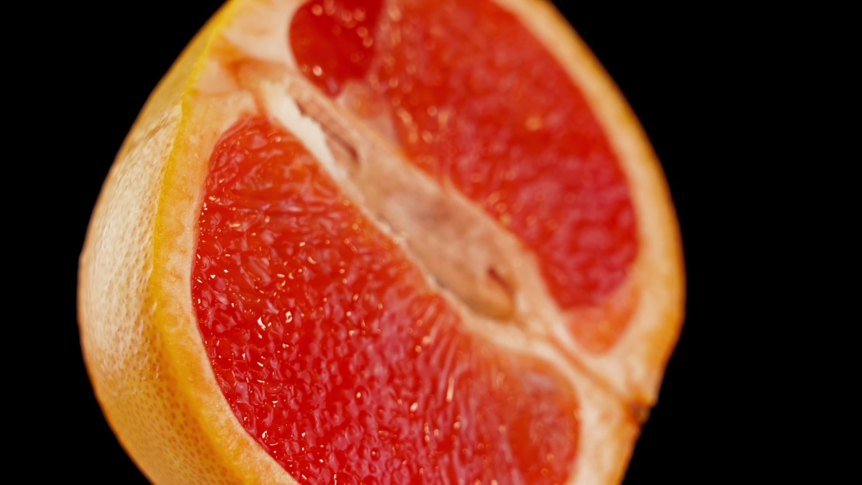 Red grapefruit cut in two on a black background