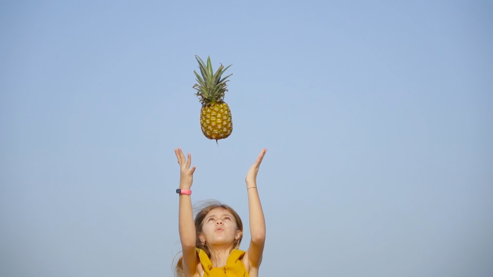 La ragazza lancia un ananas in aria al rallentatore