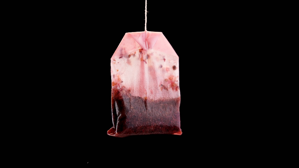 Single used teabag with tea flowing in slow motion
