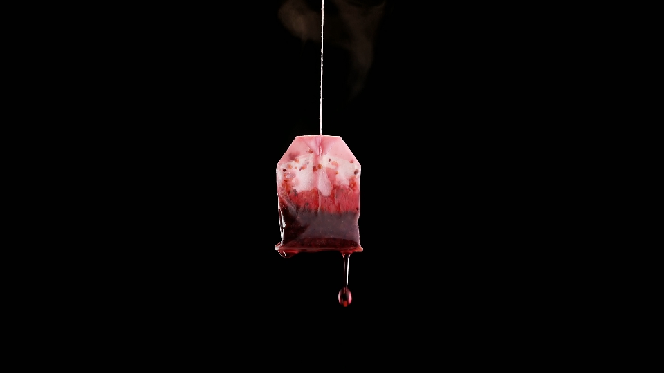 Single used teabag with tea flowing in slow motion