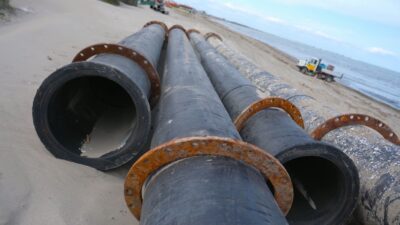 Pipes resting on the sand ready to be used on the construction site