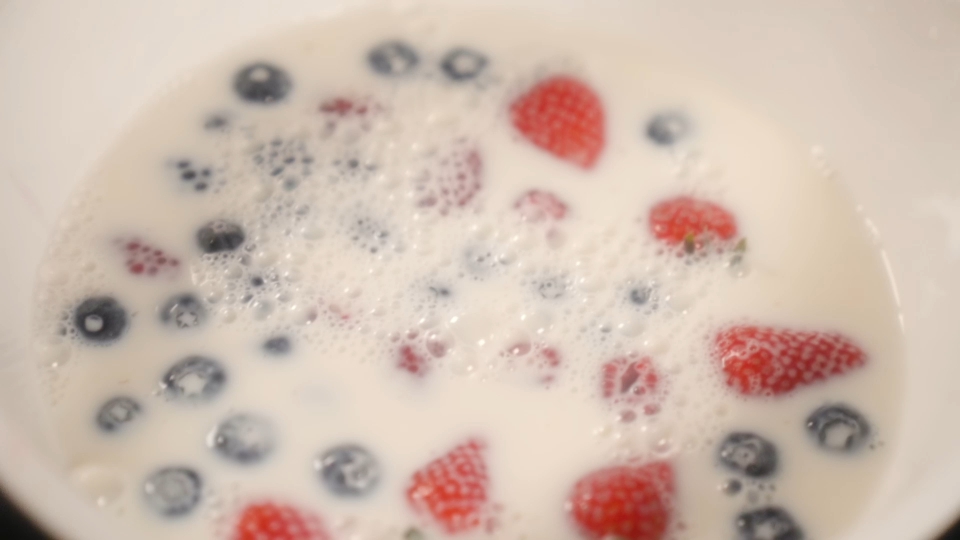 La frutta cade al rallentatore nel latte