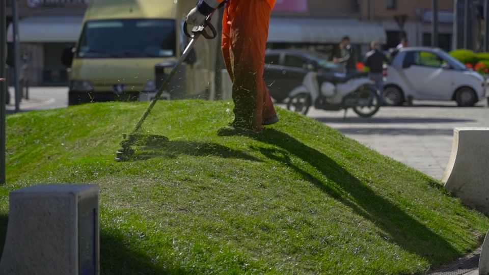 Slow motion cutting of the grass in the city