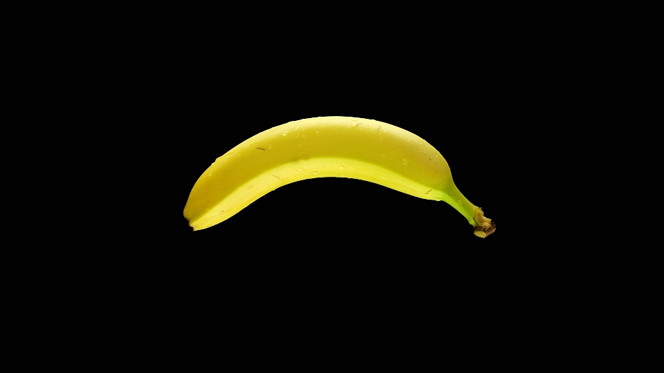Banana bagnata da gocce d’acqua ruota su sfondo nero isolato