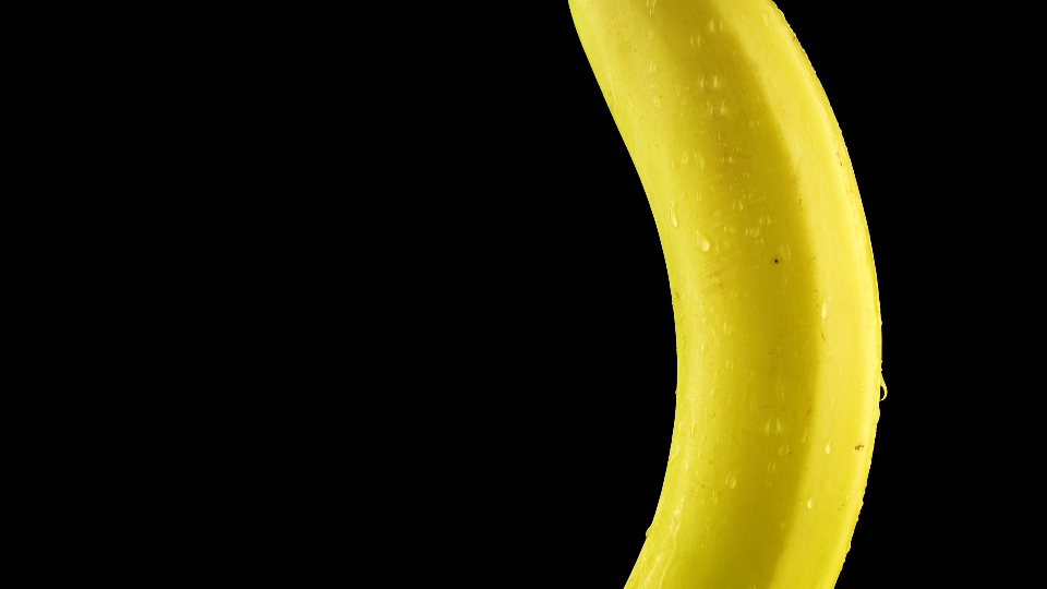 Banana bagnata con acqua su sfondo nero