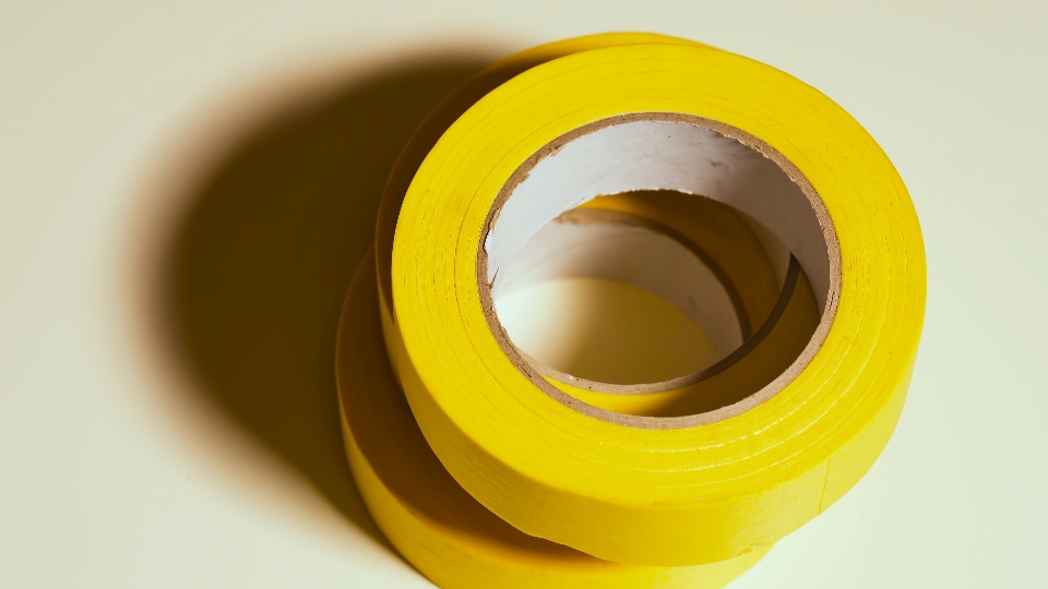 Il nastro adesivo giallo ruota su sfondo grigio