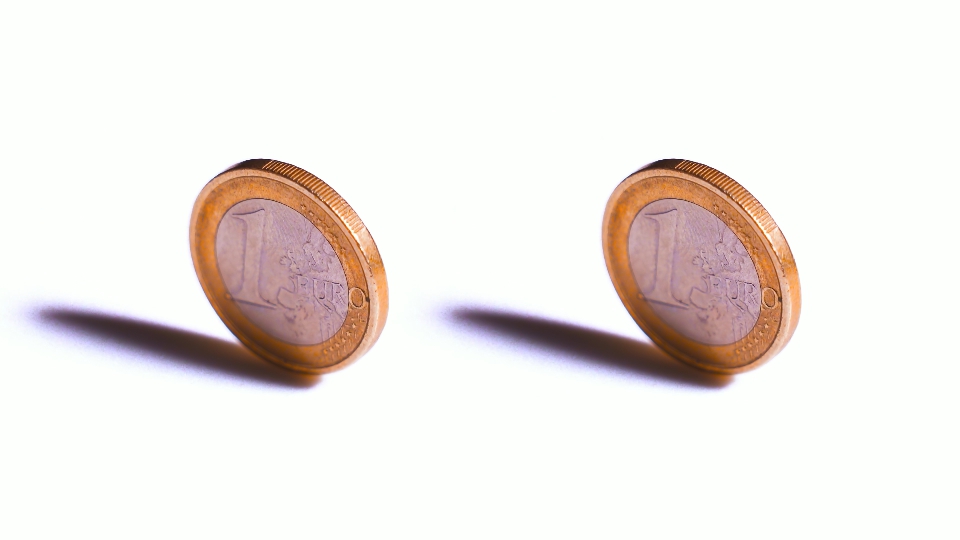 Two one euro coins are spinning on a white background