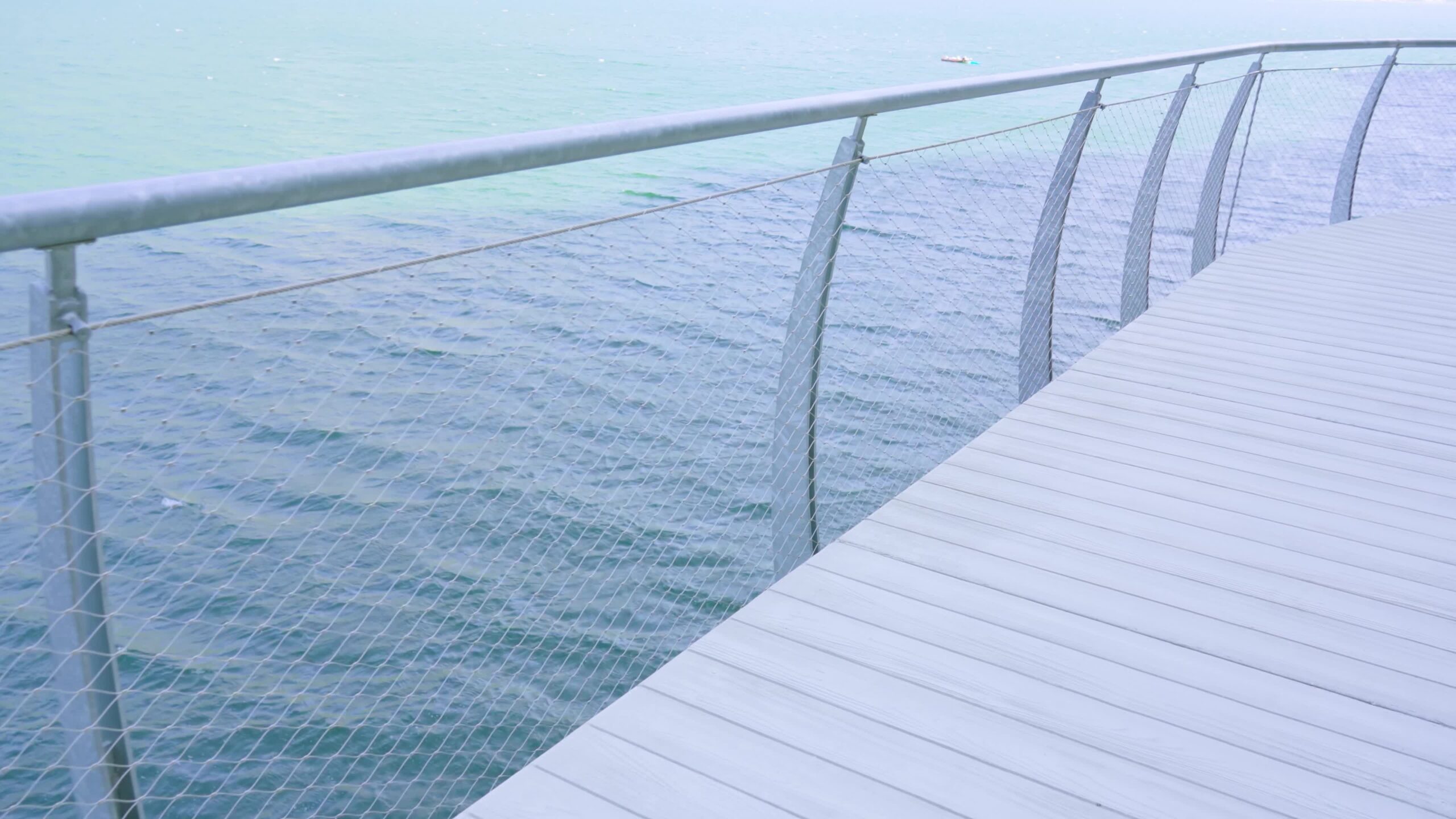 Pedestrian path with mesh fence by the sea
