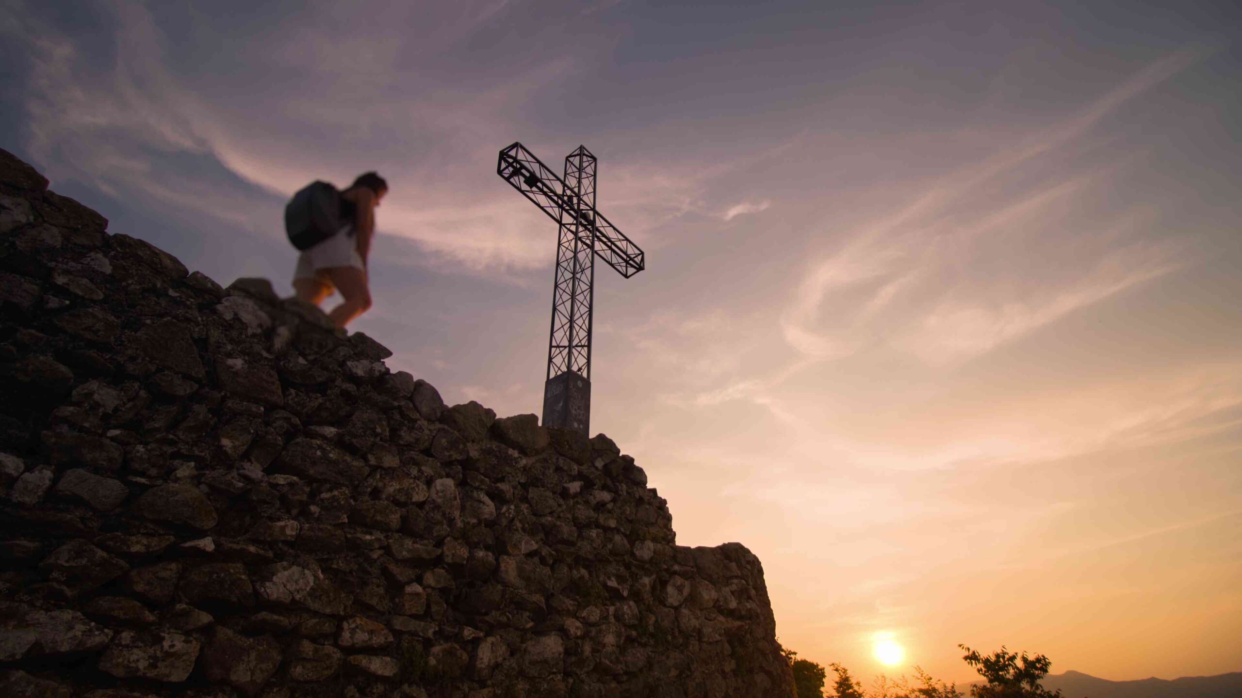 Donna vicino ad una croce al tramonto
