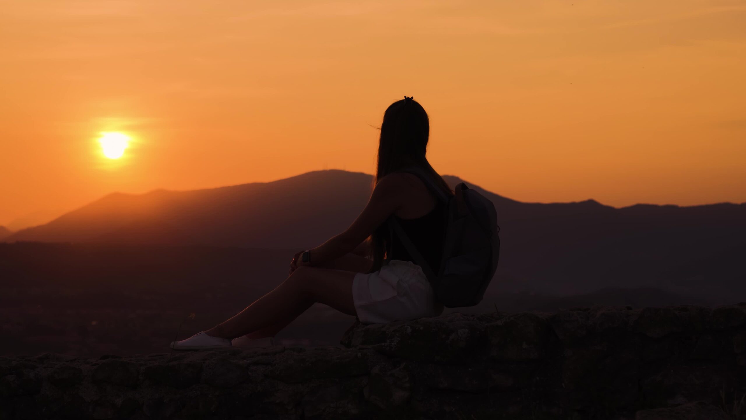 Donna seduta al tramonto osserva le montagne