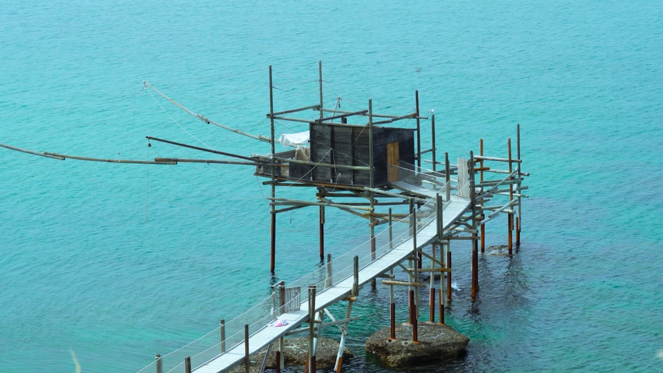 Casetta in legno con rete da pesca su mare azzurro