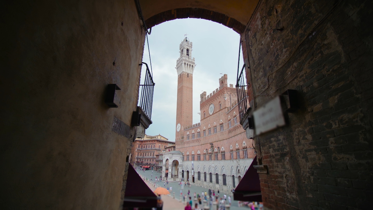 Strada stretta con vista sulla torre di Mangia a Siena