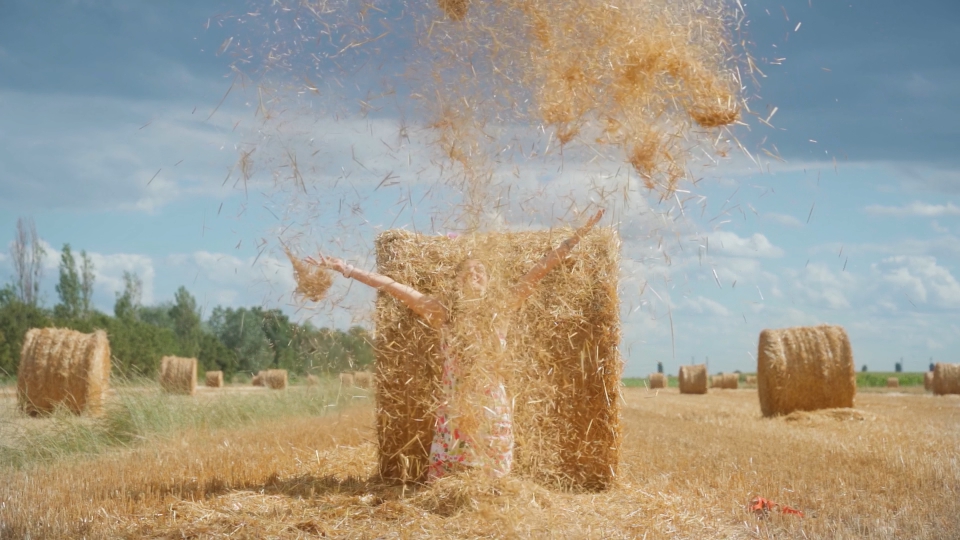 Reverse shot of the hay rising into the sky on the agricultural field