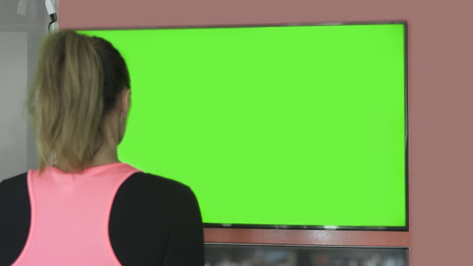 Woman approaches a green screen TV screen
