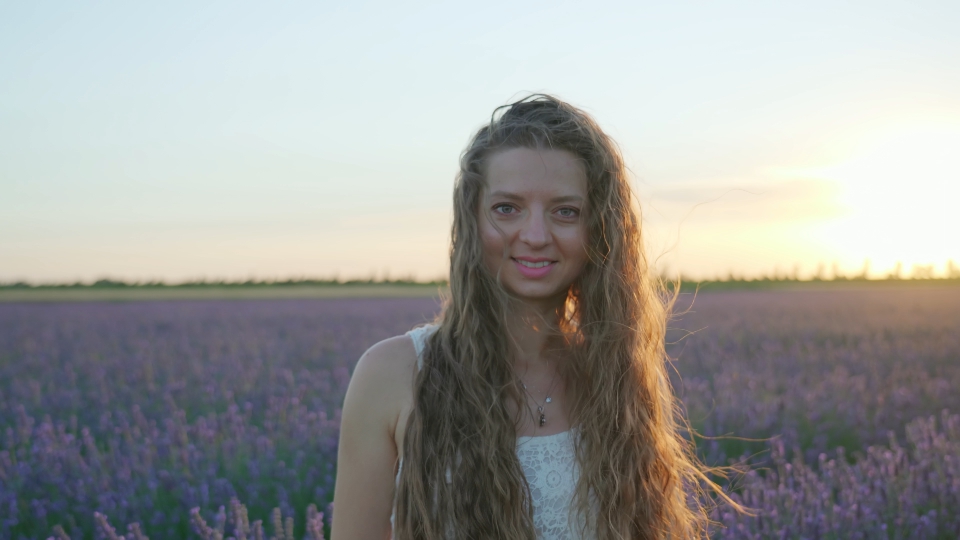 Woman posing looking in camera at sunset among nature