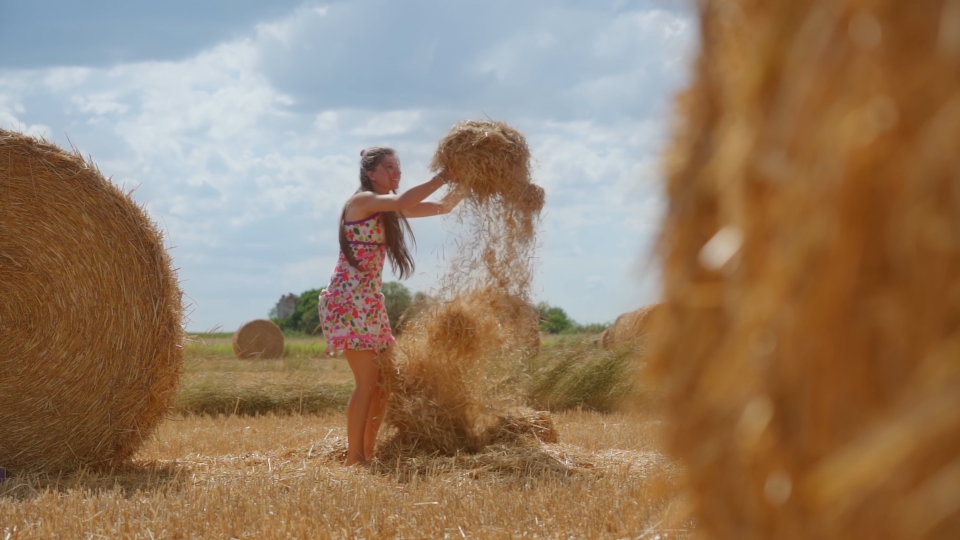 Donna lancia la paglia divertendosi sul campo agricolo